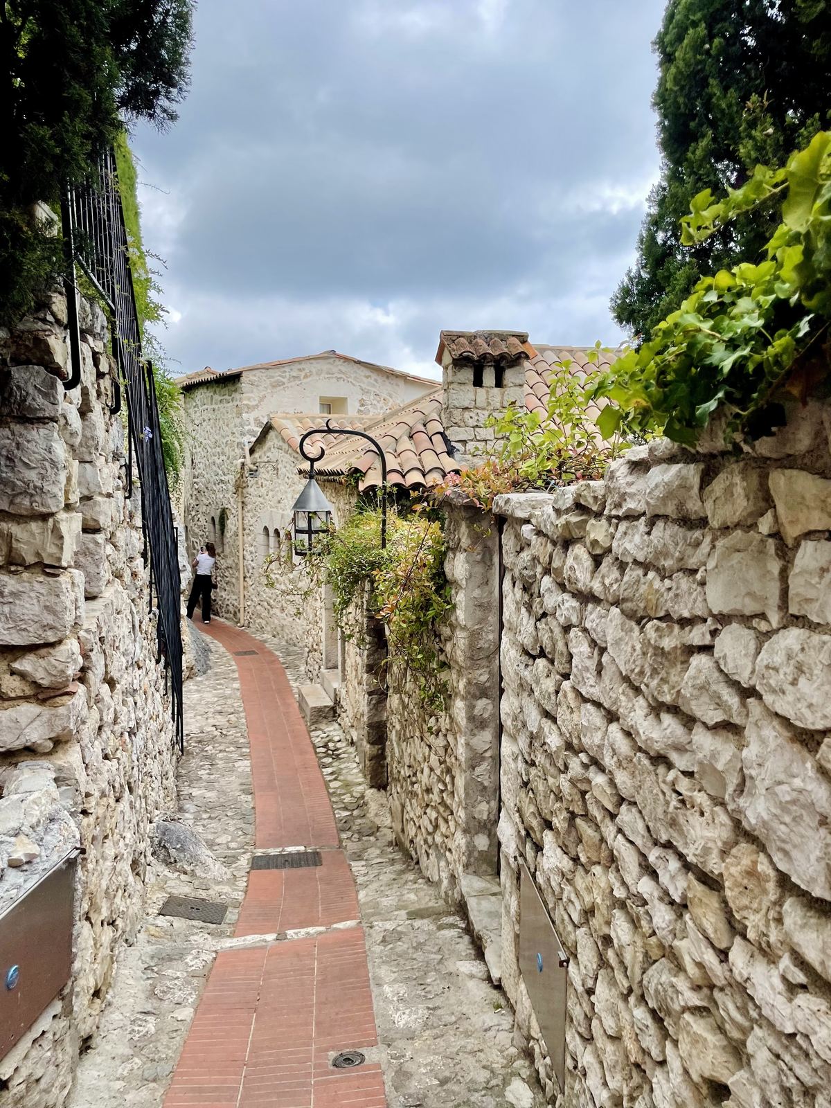 Eze village — another stone passage, old walls, terracotta roof tiles, lantern on the wall